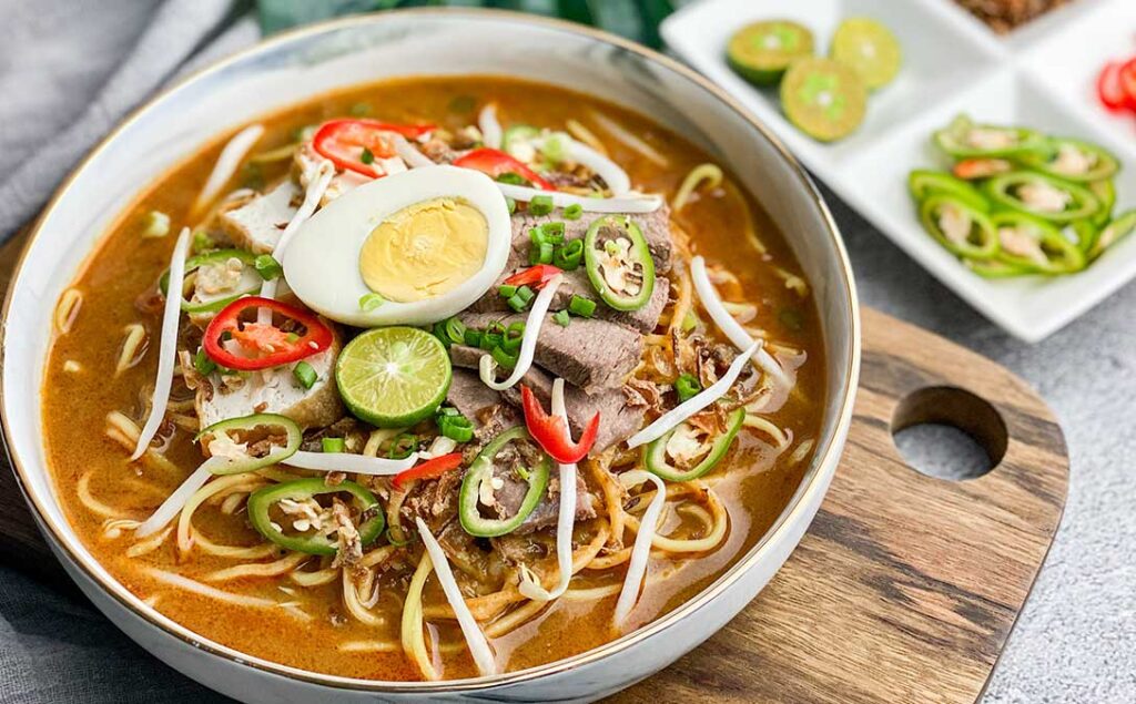 Malay Cuisine in SG : Mee Rebus with yellow noodles in sweet potato and prawn-based gravy topped with egg and tofu.