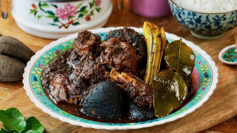 Peranakan Cuisine in Singapore : Ayam Buah Keluak with earthy black nuts, showcasing the unique depth of Peranakan flavors.