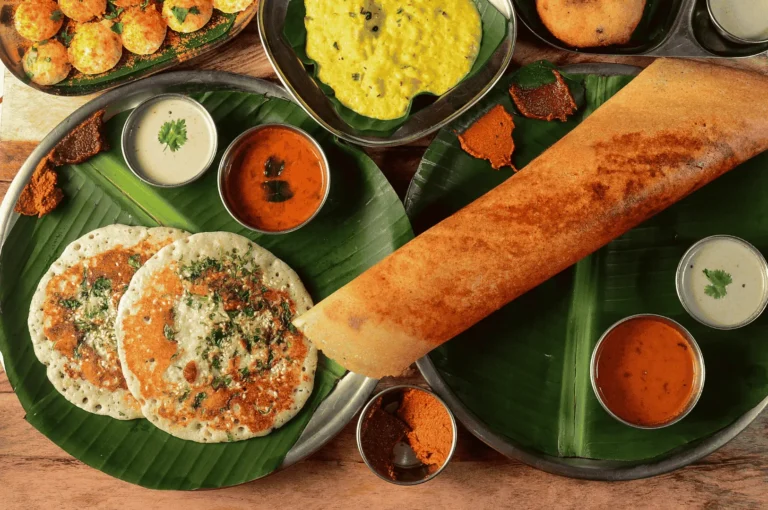 Traditional South Indian breakfast served on banana leaves and metal plates, featuring uttapams, crispy dosa, assorted chutneys, sambar, lentil curry, and paniyarams—celebrating the vibrant flavors and cultural authenticity of Little India, Singapore.