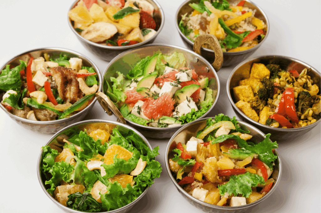 Seven vibrant bowls of fresh salads featuring colorful combinations of vegetables, fruits, tofu, grilled chicken, and nuts—highlighting the diversity of healthy dining options near Little India, Singapore, where global flavors meet local wellness trends.
