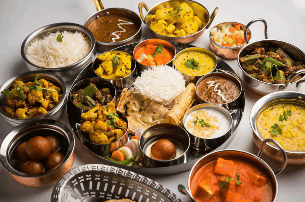 Traditional Indian thali featuring steamed rice, chapati, papadum, paneer curry, dal, mixed vegetable curries, raita, pickles, and gulab jamun—offering a vibrant, balanced snapshot of authentic dining experiences in Little India, Singapore.
