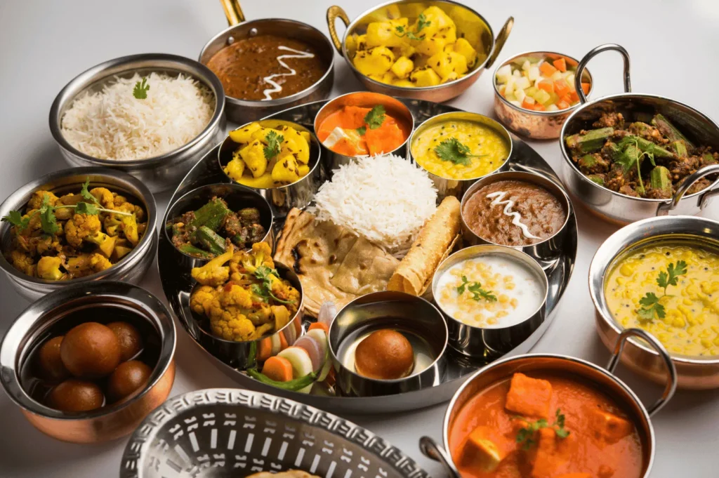 Traditional Indian thali featuring steamed rice, chapati, papadum, paneer curry, dal, mixed vegetable curries, raita, pickles, and gulab jamun—offering a vibrant, balanced snapshot of authentic dining experiences in Little India, Singapore.