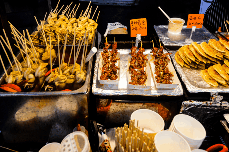Korean street food stall featuring comforting korean dishes like spicy tteokbokki sauce with chewy rice cakes, grilled meats including marinated chicken skewers, and fried dumplings, showcasing authentic korean cuisine and korean cooking. This bustling setup reflects the vibrant flavors of korean food found in korean restaurants in singapore such as charim korean bbq, wang dae bak, hanjip korean grill house, mul gogi korean bbq, don dae bak, dae bak, woo dae galbi, pohang seafood, and seoul restaurant. Ideal for sharing platter, side dishes, ala carte items, la carte dishes, la carte options, la carte menu, lunch sets, set menus, buffet menu, and bbq sets, these offerings pair well with pork belly, beef brisket, beef short rib, pork jowl, pork collar, kurobuta berkshire pork, usda prime beef, prime beef, and premium meat cuts. Popular in kbbq restaurants and korean bbq restaurant locations near clarke quay and jalan jurong kechil, serving korean charcoal bbq, grilled meats on the main grill, pork set, bbq menu, and premium cuts. Enjoy steamed dumplings, kimchi stew, kimchi fried rice, fried rice, black bean noodles, seafood pancake, kimchi pancake, korean fried chicken, fried chicken, mozzarella cheese, free flow eggs, and comfort food in private dining rooms with attentive service—perfect for special occasions and taste buds seeking the best korean barbecue and korean cuisine in singapore. Discover the four flavours from sister brand rochester chingu and celebrate every korean term with authentic street-style korean dishes.