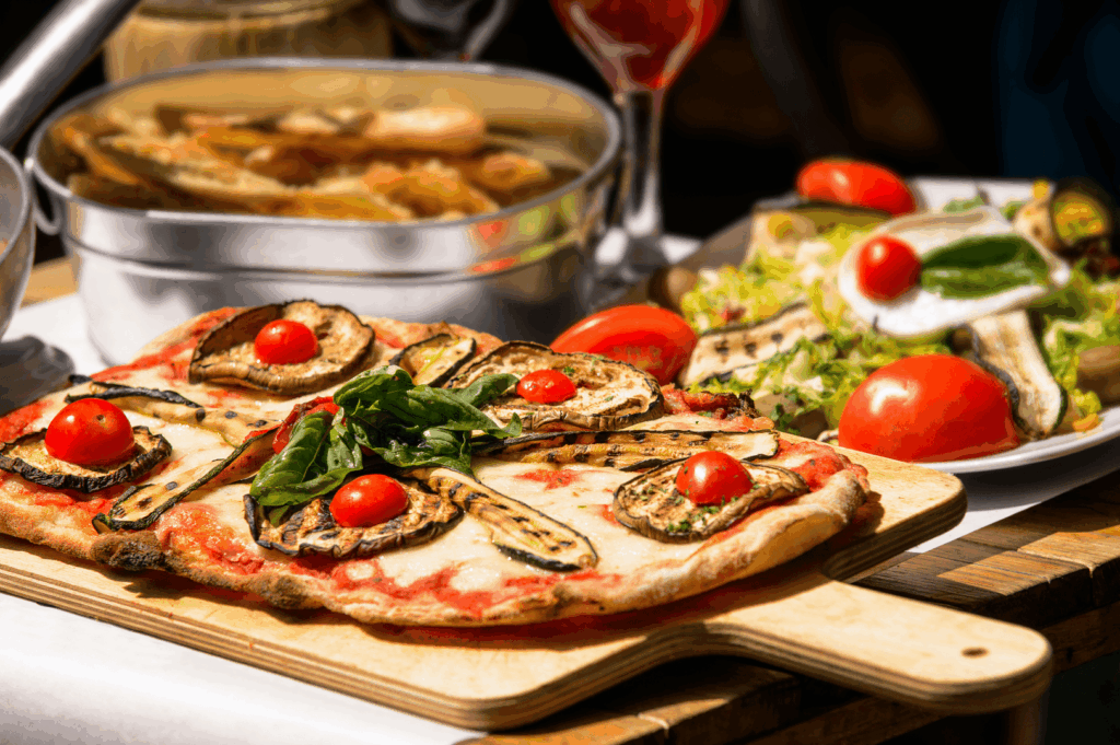 Freshly baked pizza on a wooden serving board in an Italian restaurant, part of authentic Italian cuisine and Italian food traditions, topped with fresh vegetables like grilled zucchini, ripe tomatoes, basil, and mozzarella cheese, drizzled with olive oil and extra virgin olive oil. This traditional dish is among iconic Italian dishes from northern Italy to southern Italy, typically served with great food such as fresh pasta, stuffed pasta, risotto, pizza, and indulgent desserts. Various sauces like tomato sauce, meat sauce, pesto sauce, balsamic vinegar, lemon juice, melted butter, and parmesan cheese enhance pasta varieties, main courses, and baked meals made from wheat flour dough, buffalo milk, and primary ingredients like cannellini beans, pine nuts, potatoes, herbs, oregano, garlic, and salt. The food styling reflects a deep connection to Italy’s long history of cooking, where recipes vary depending on the region, from Emilia Romagna specialties to seafood, chicken, beef, and prosciutto dishes. Served with bread, desserts, and other cooked creations, this meal showcases many variations of Italian pasta, meat, sauce, and cheese combinations that define Italy’s great food heritage.