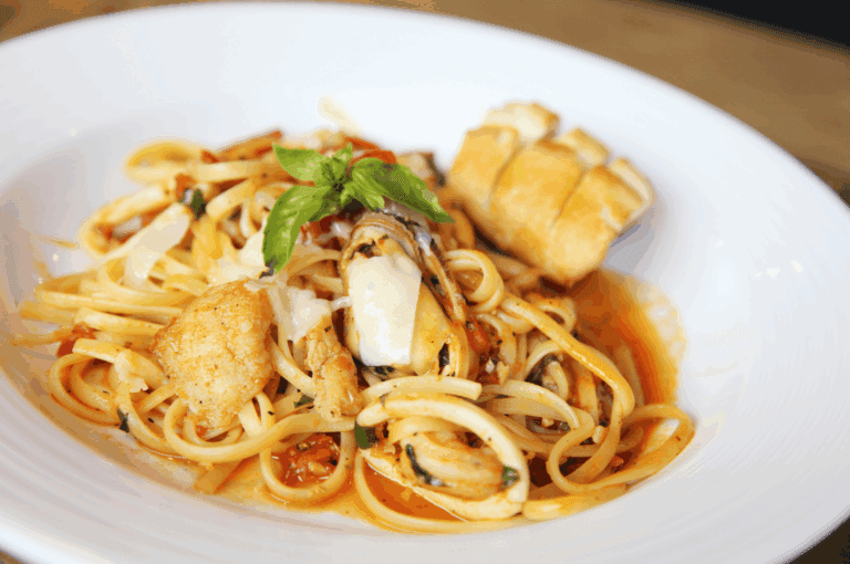 Authentic Italian cuisine seafood pasta, a traditional dish from northern Italy and southern Italy, beautifully plated with expert food styling in an Italian restaurant, featuring linguine in rich tomato sauce made from ripe tomatoes, olive oil, extra virgin olive oil, garlic, herbs, oregano, and fresh vegetables. This iconic Italian food combines parmesan cheese, mozzarella cheese, buffalo milk, melted butter, milk, salt, lemon juice, lemon, and bread, served with shrimp, mussels, and other seafood, reflecting a deep connection to Italy’s long history of Italian dishes and pasta varieties. Typically served as part of main courses alongside fresh pasta, stuffed pasta, baked meals, pizza, risotto, and indulgent desserts, this great food showcases various sauces such as meat sauce, pesto sauce, and balsamic vinegar dressings, with many variations that vary depending on the primary ingredient—meat, beef, chicken, prosciutto, vegetables, potatoes, or cannellini beans. Inspired by Emilia Romagna recipes and crafted with wheat flour, dough, pine nuts, and butter, this meal celebrates Italian culture, cheese, sauce, and food heritage, offering pasta dishes that are cooked to perfection and served as part of Italy’s most beloved recipes.