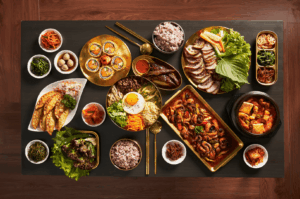 A vibrant spread of Korean cuisine in Singapore featuring comforting Korean dishes like bibimbap with USDA prime beef, spicy stir-fried octopus, kimchi stew, steamed dumplings, and assorted banchan. Includes grilled meats such as pork belly and beef brisket, served with lettuce wraps and premium meat cuts. Gimbap, fried rice, and chewy rice cakes complement the la carte dishes. Ideal for special occasions at top Korean restaurants in Singapore like Charim Korean BBQ, Wang Dae Bak, and Hanjip Korean Grill House, known for their Korean charcoal BBQ, attentive service, and private dining rooms.