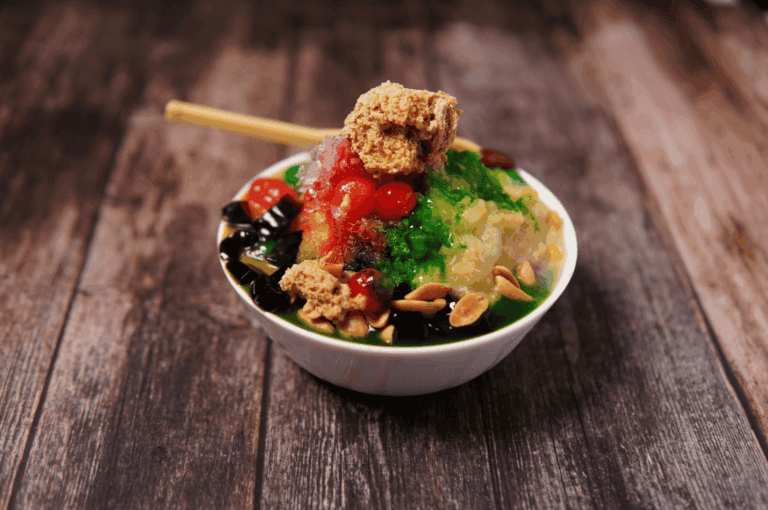 Close-up of a traditional Singaporean Ice Kachang bowl on a wooden table, topped with colorful jellies, red beans, and shaved ice, showcasing local sweet flavors
