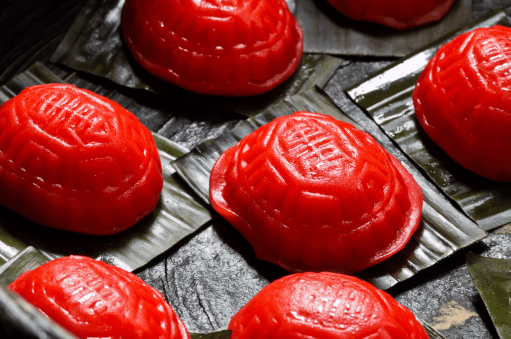 A bowl of red ang ku kueh on bamboo leaves, highlighting traditional Singaporean dessert heritage
