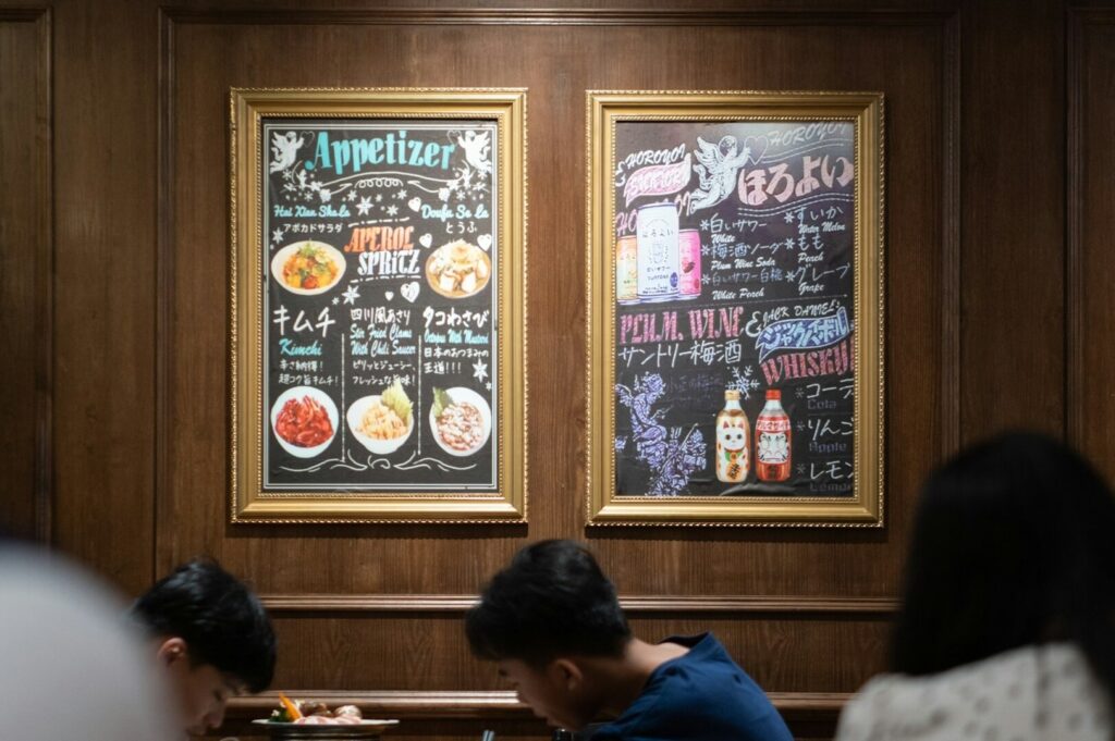 Interior of a Singapore restaurant with a chalkboard menu, showcasing patrons engaged in their dining experience.