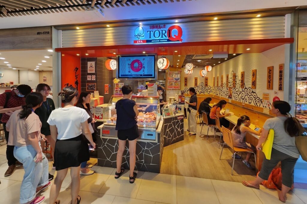 A group of people standing in front of Plaza Singapura, showcasing a vibrant dining atmosphere.