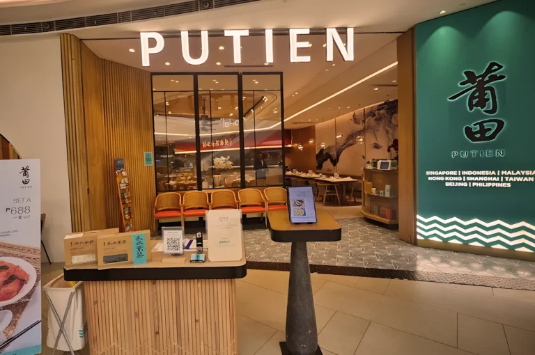 Entrance of PUTIEN restaurant featuring modern minimalist design, illuminated signage, and elegant interior with wooden accents — award‑winning Fujian cuisine chain in Asia.