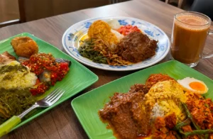 Three plates of Nasi Padang with rice, rendang, sambal, and egg, served with teh tarik.