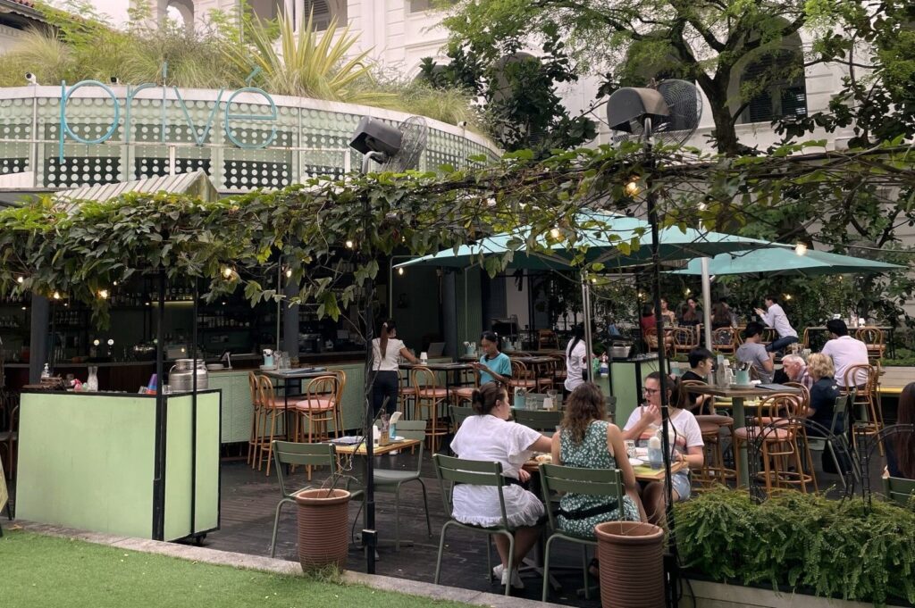 Guests enjoying meals at tables in the outdoor section of CHIJMES Dining, a popular restaurant in Singapore.