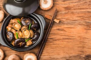 A wooden table displays Pen Cai, a Chinese dish with an assortment of mushrooms, highlighting its rich flavors.