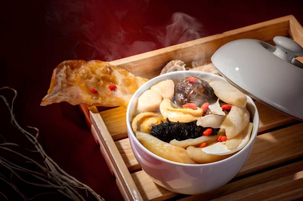 A bowl of Buddha Jumps Over The Wall soup featuring tender meat and colorful vegetables in a savory broth.