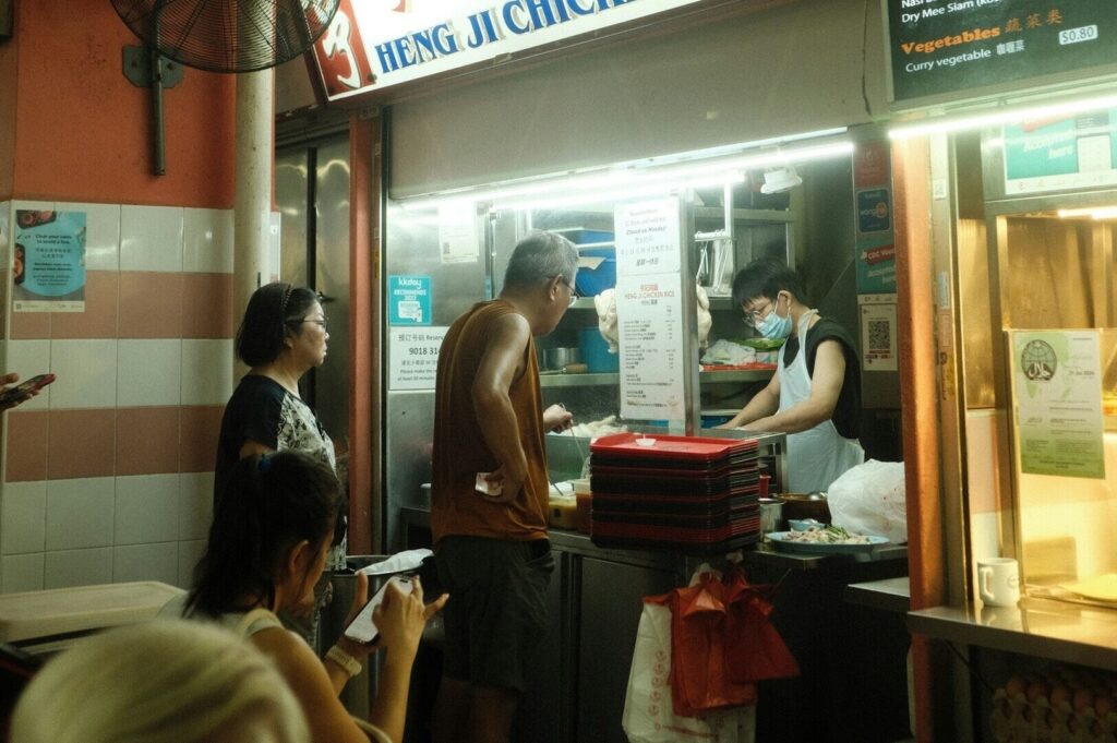 People gathered in front of a Singapore hawker food stand, enjoying the vibrant street food culture.