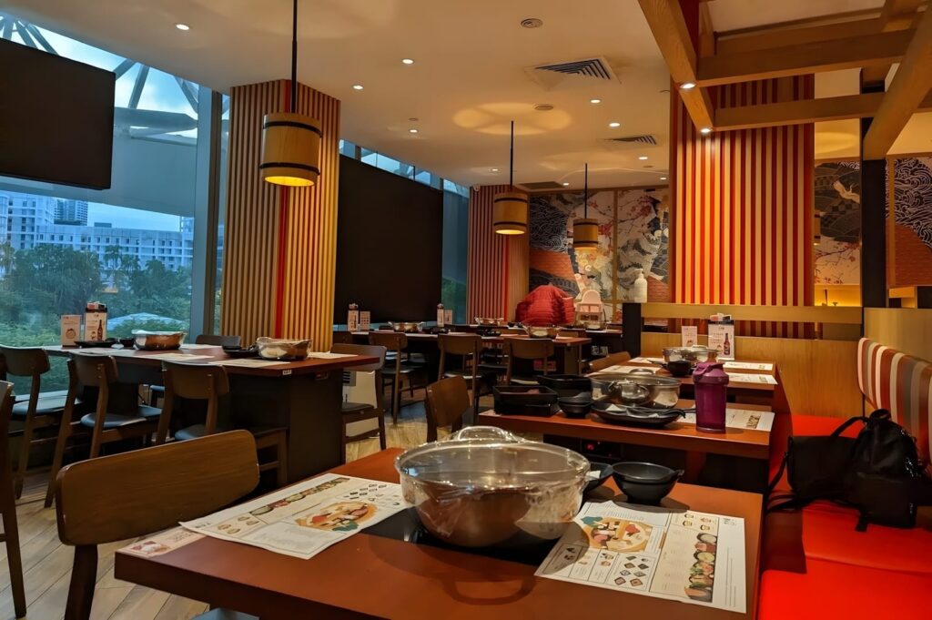 A restaurant in Plaza Singapura featuring tables, chairs, and a large window allowing natural light to fill the space.