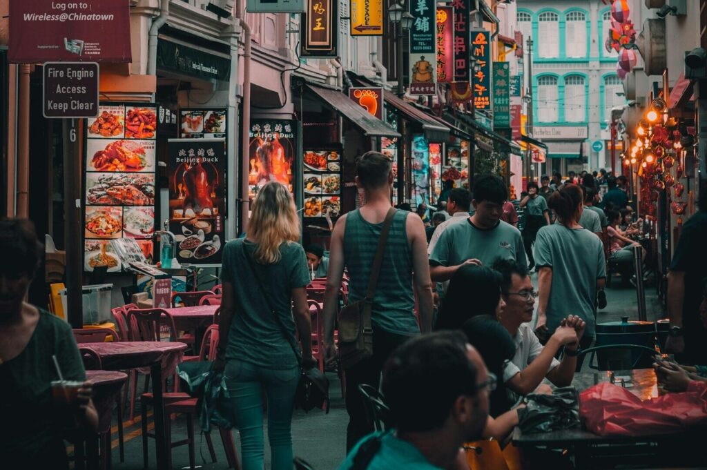 A bustling street in Singapore filled with people walking and enjoying local dining options.