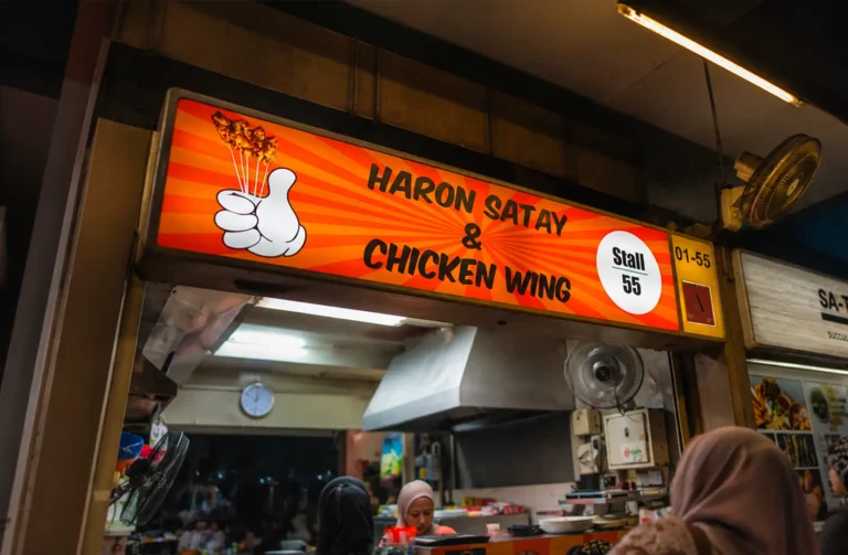 Signage for Haron Satay & Chicken Wing stall at a busy hawker center