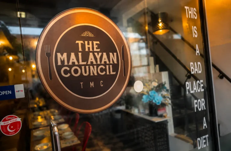 The Malayan Council restaurant logo on a glass door with humorous diet text