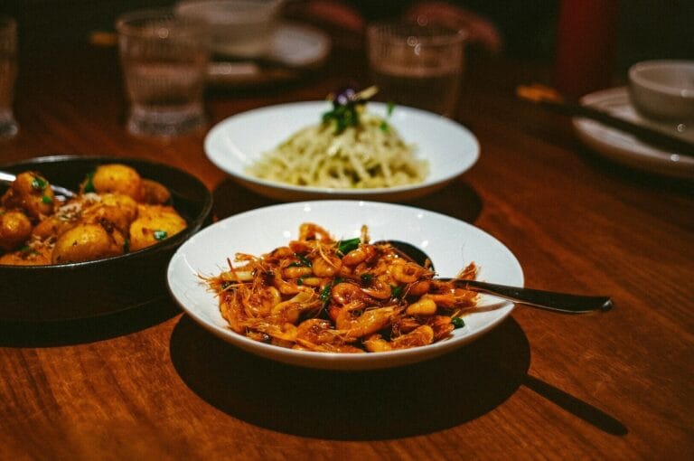 A table displaying three bowls of local Singaporean dishes, showcasing vibrant colors and diverse ingredients.