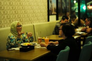 Two women seated at a table with others, showcasing Singapore's diverse dining culture.