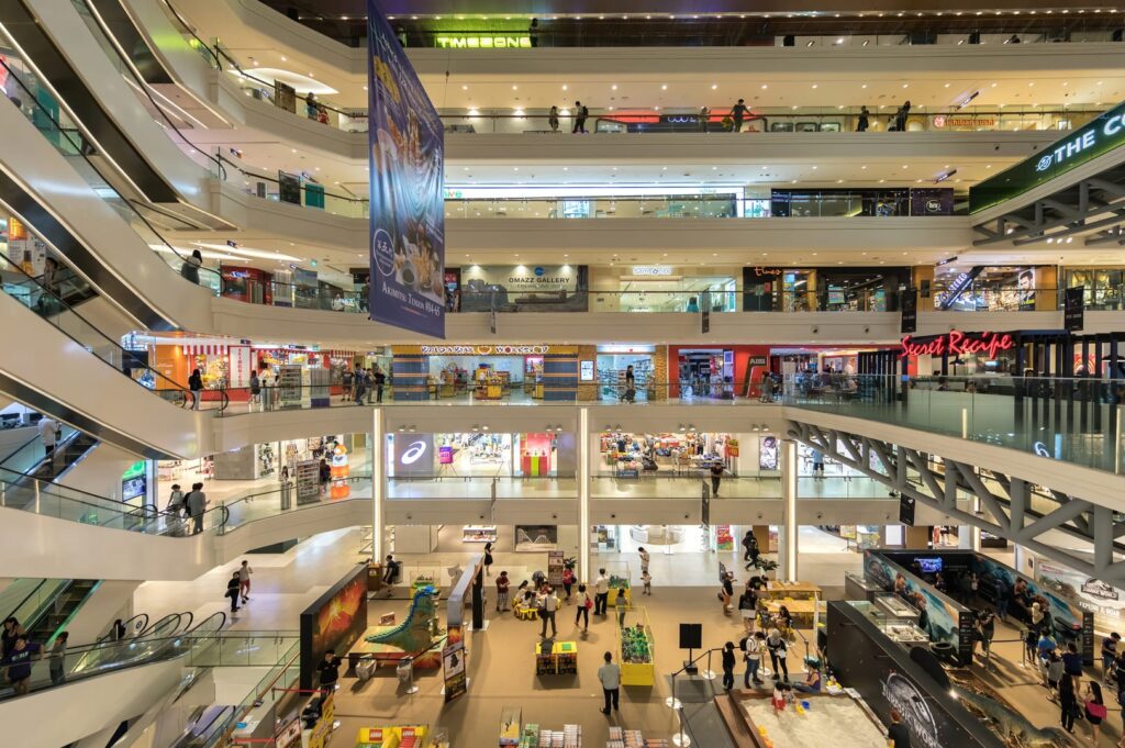 A bustling Plaza Singapura shopping mall filled with numerous shoppers and vibrant storefronts.