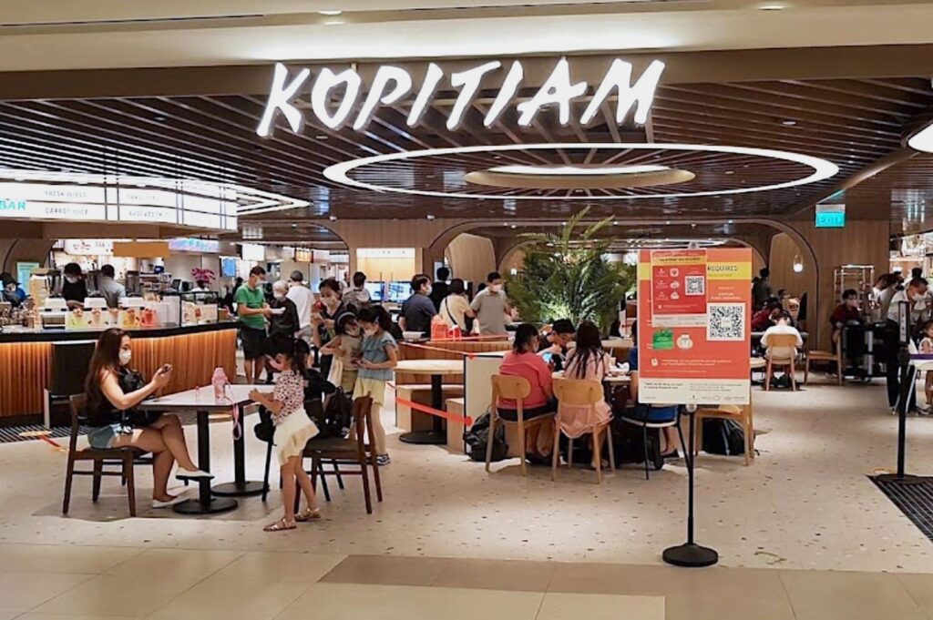 Kopitiam, featuring a vibrant food plaza with various Singaporean dishes and dining options.