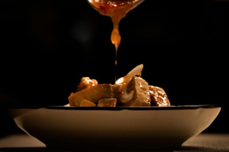 A spoon is being poured over a bowl of food, showcasing a delicious dish served in a Singapore restaurant.