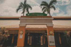 A restaurant in Singapore, the Maxwell Food Centre, featuring palm trees and a sign.
