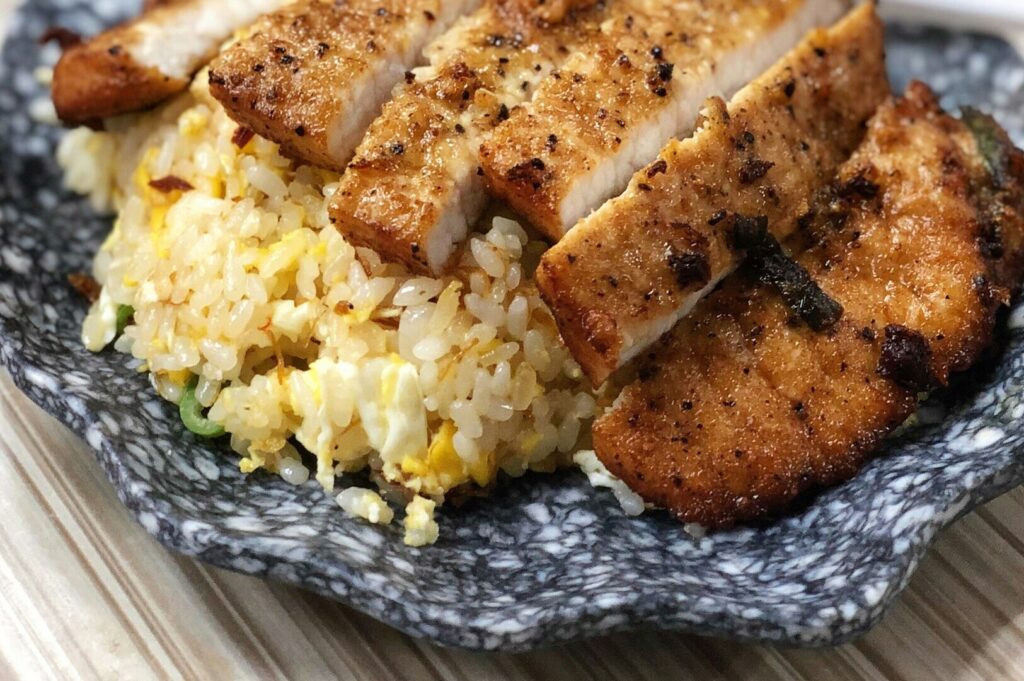 A plate of rice topped with savory meat, showcasing local dining cuisine in Singapore.