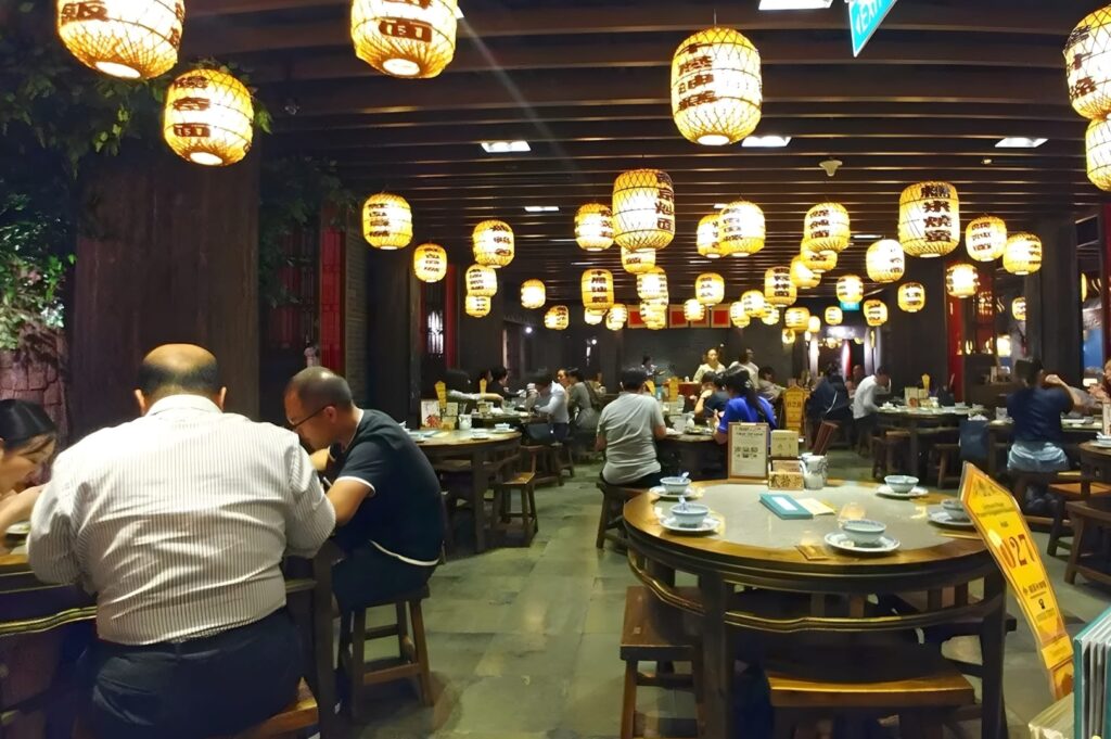 A bustling restaurant in Plaza Singapura, filled with diners enjoying meals and drinks at various tables.