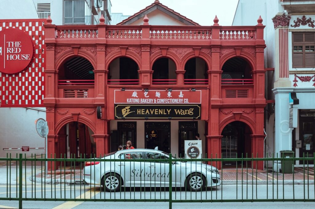 A parked car in front of a vibrant red building, showcasing a restaurant in Singapore.