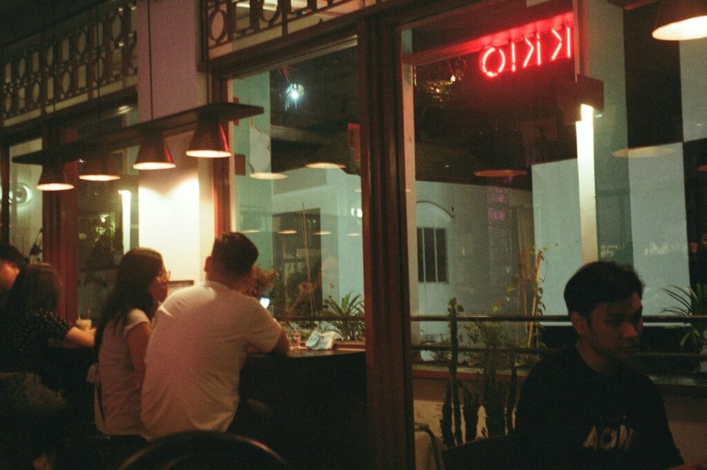 People dining at tables outside a restaurant in Singapore, enjoying local cuisine in a vibrant atmosphere.