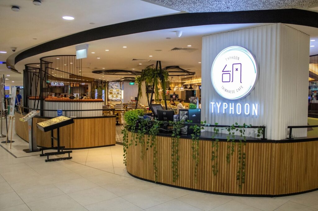 Inside view of Typhoon Cafe in Plaza Singapura, showcasing a sign in a vibrant restaurant setting.
