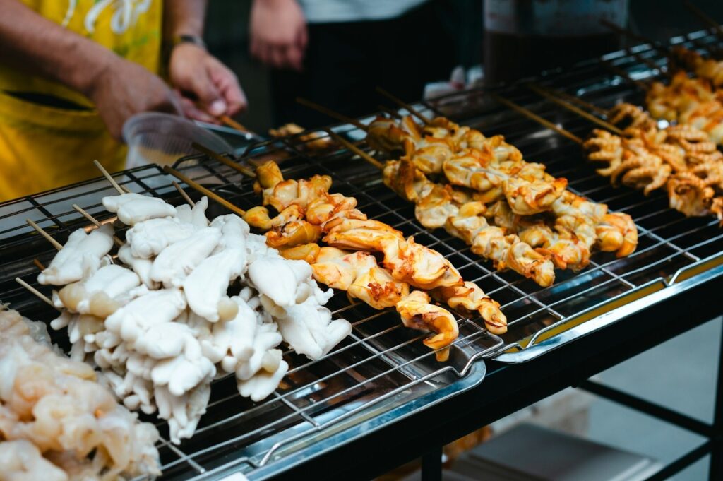 A man grilling food at the Singapore Festival Food, showcasing vibrant dishes and a lively outdoor cooking atmosphere.