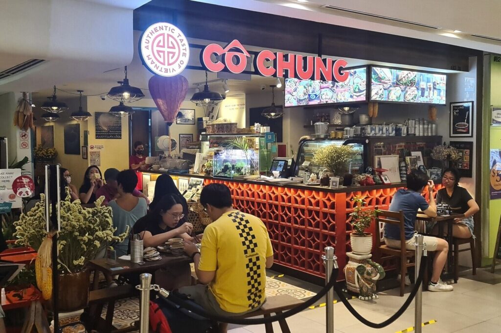 Diners seated at tables in Co Chung Restaurant, with a visible sign displaying the restaurant's name.