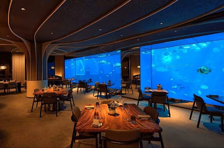 Ocean Restaurant Singapore featuring a large aquarium wall, creating an immersive underwater dining experience.