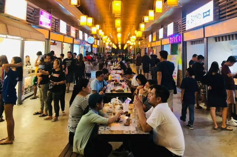 People dining at tables in a vibrant food court in Singapore, enjoying a variety of cuisines.