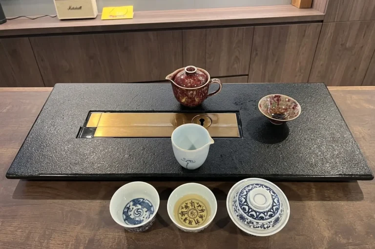 Traditional tea ceremony setup with ceramic teapots and cups on black stone table