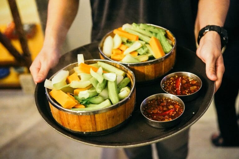 A person presents a tray featuring two bowls of food, highlighting the rich diversity of Singapore's culinary culture.