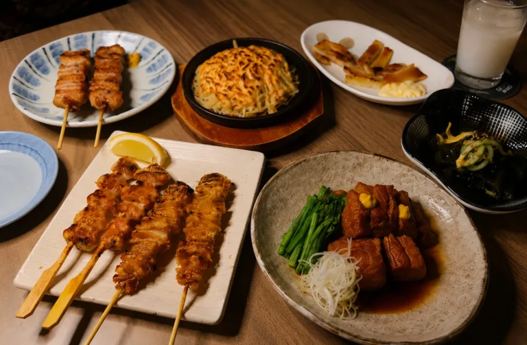 le spread featuring yakitori skewers, a jaga mentaiko, buta kakuni, and other Japanese izakaya plates