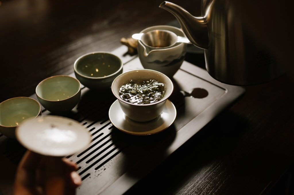 A person pours tea from a teapot into a cup in Ki-setsu tea room at Orchard Road, showcasing a serene tea service moment.