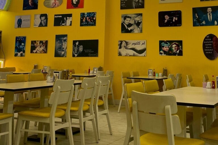 A vibrant restaurant in Singapore featuring yellow walls and neatly arranged tables.