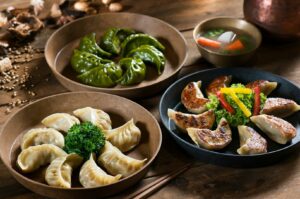 Three plates of dumplings arranged on a table, showcasing a variety of flavors in Singapore's vibrant food culture.