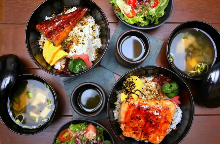 A dining table featuring an assortment of food bowls and rice, highlighting the culinary offerings of Singapore Izakaya.