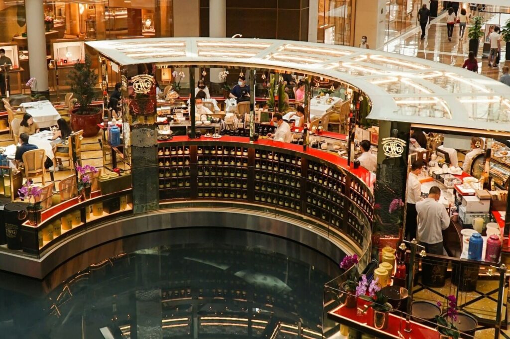 Interior of a Singapore restaurant featuring a large circular bar, with guests seated at tables socializing and dining.