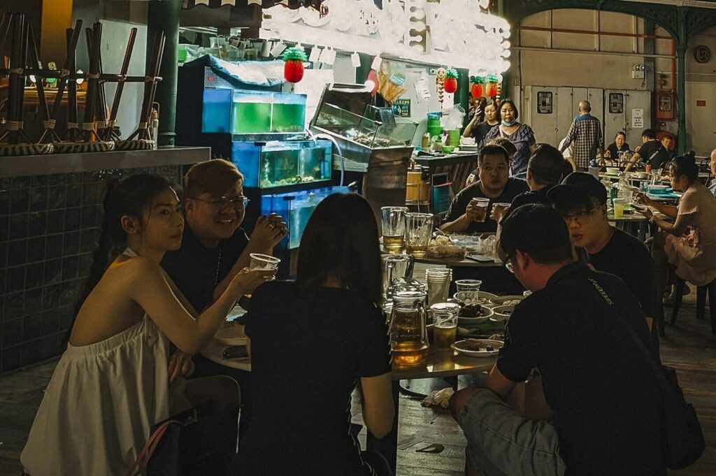 A cozy restaurant scene in Singapore with people dining together in a softly lit environment.