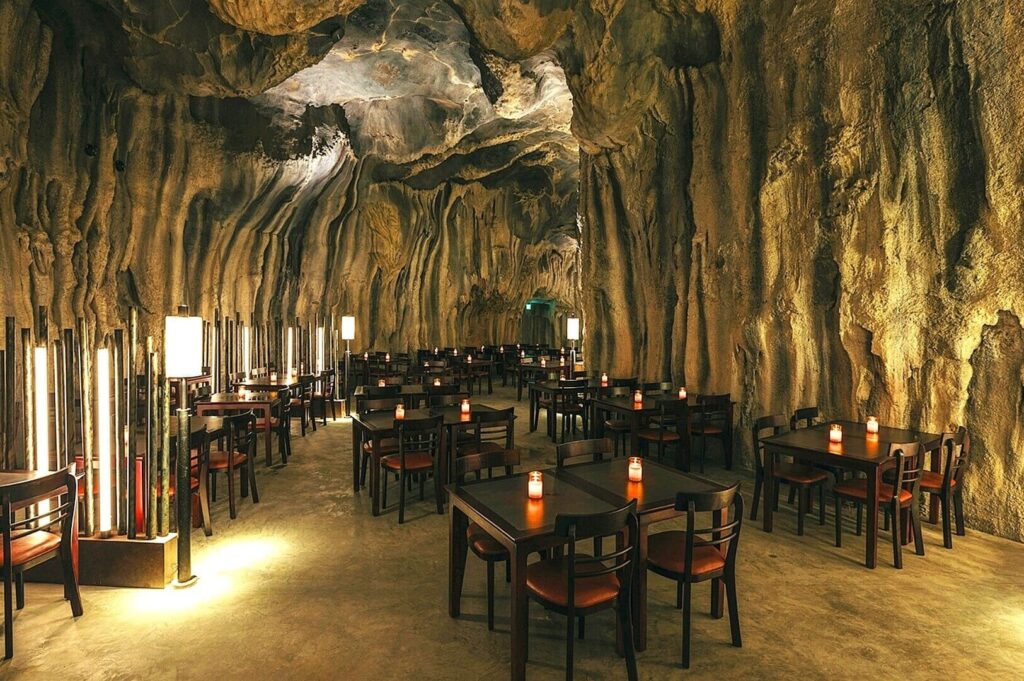 Interior of Cavern Restaurant in Singapore, showcasing tables and chairs arranged inside a cave setting.