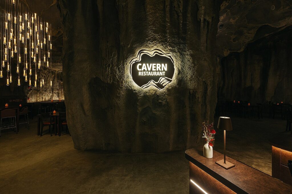 Interior view of The Cave restaurant in Singapore, featuring stone walls and ambient lighting for a unique dining experience.